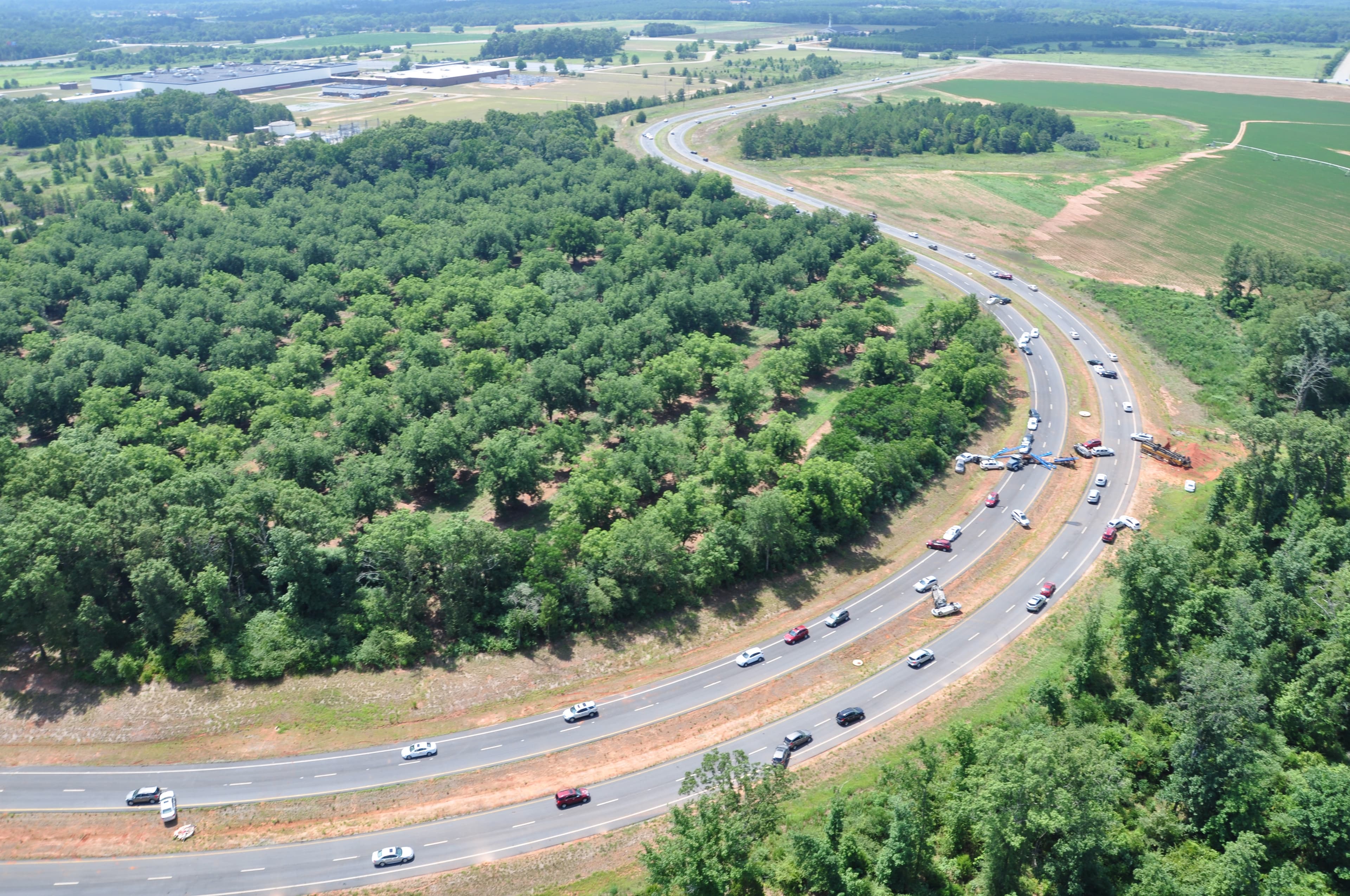 Aerial view of the four-lane interstate highway simulator curving through tree groves, with cars on the road.