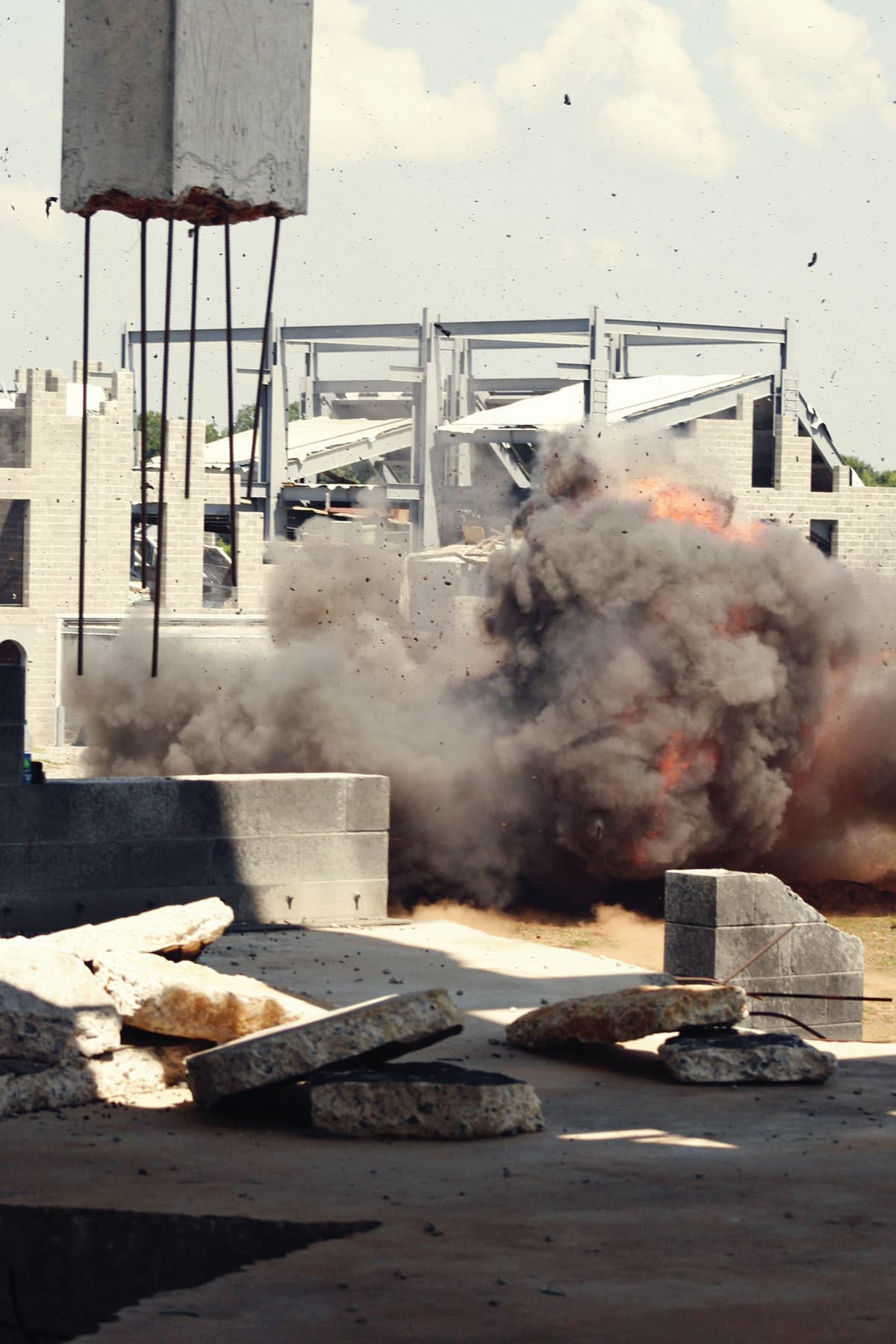 An explosive breaching charge blows open a concrete-block wall in a cloud of dust and debris.