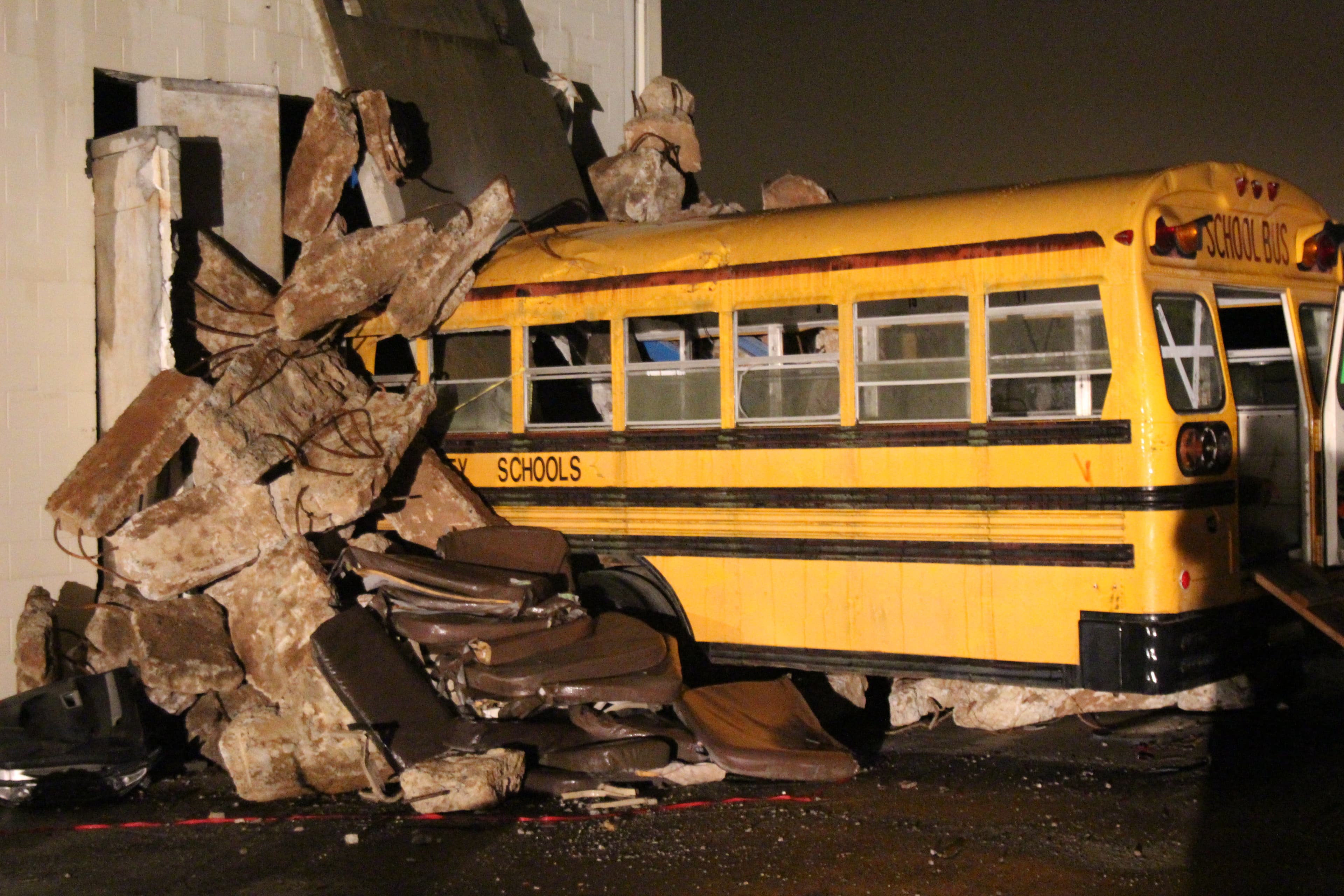 A yellow school bus crushed under fallen concrete slabs in a collapsed-structure training scenario.