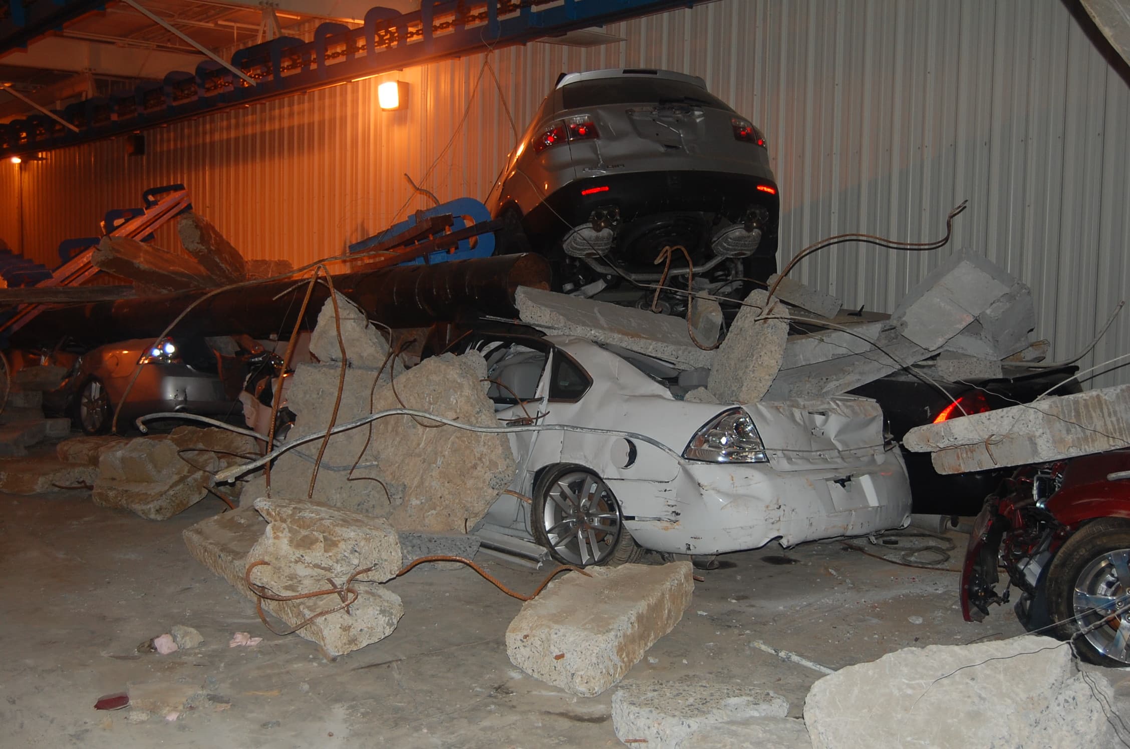 Inside the highway tunnel, cars lie crushed beneath fallen concrete slabs and rock in a collapse scenario.