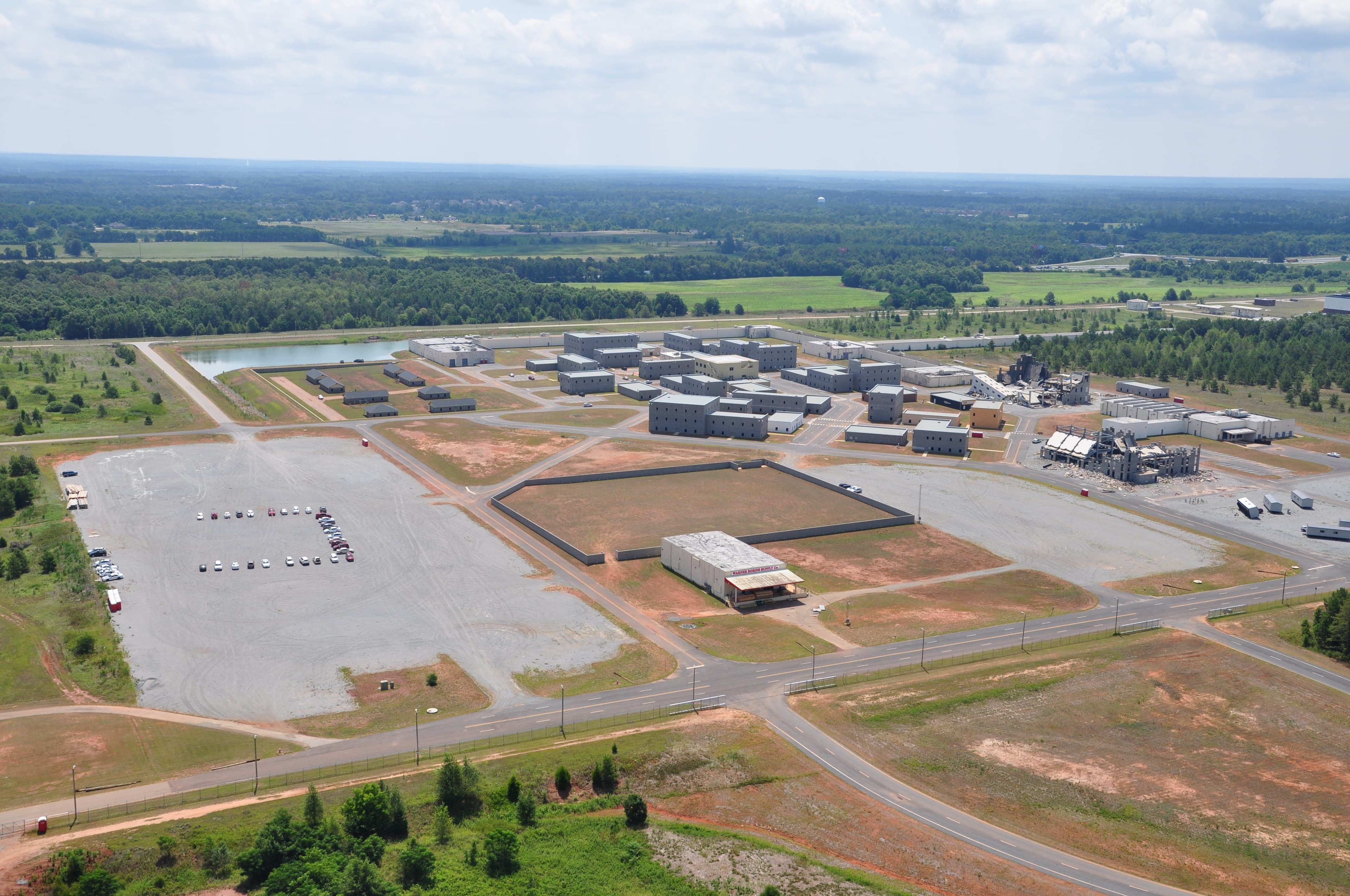 Aerial view of the paved staging lots and training buildings on the campus, with parked cars and open fields beyond.
