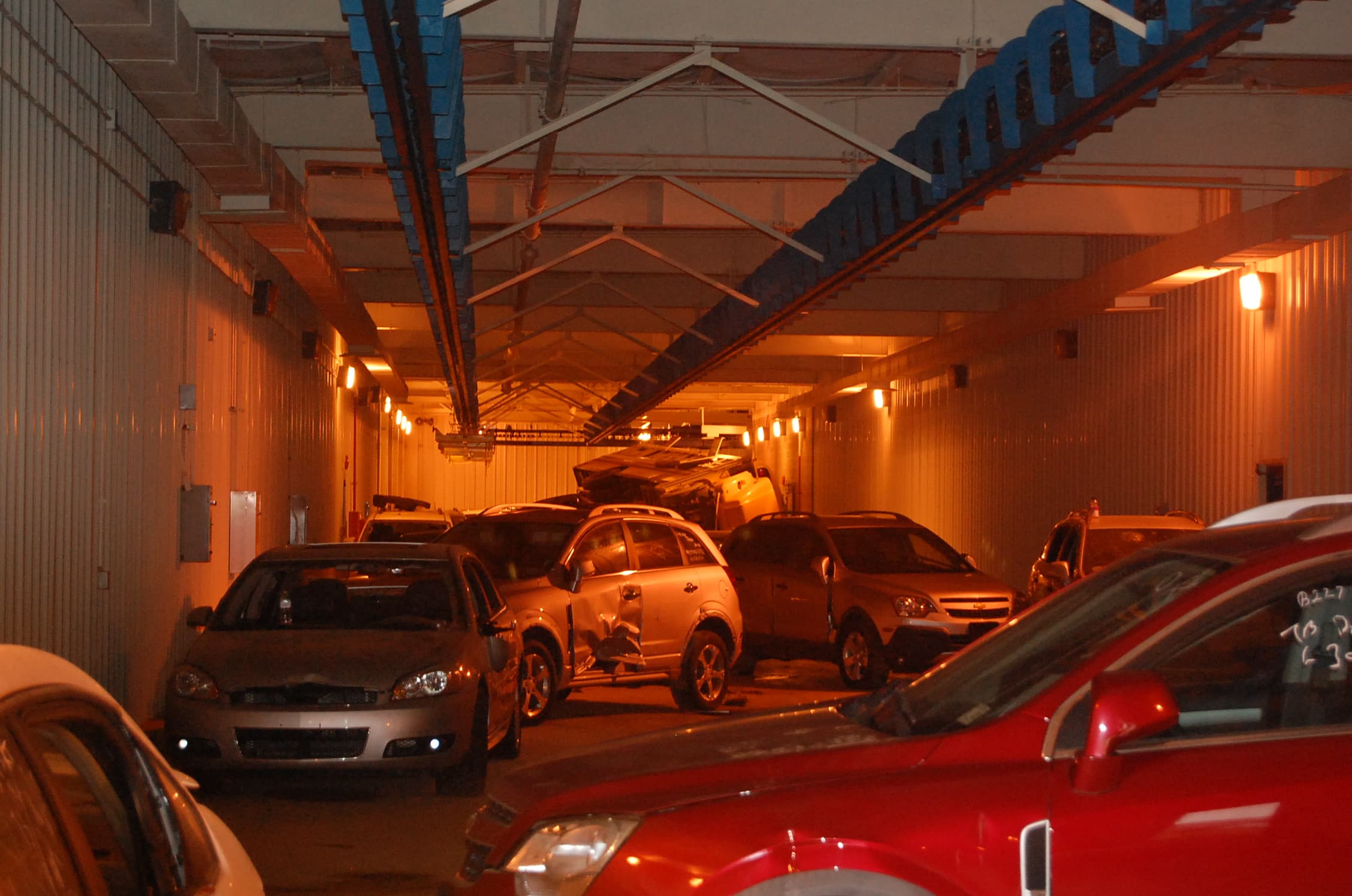 Damaged cars sit bumper to bumper inside the highway tunnel, lit red by the overhead lights.