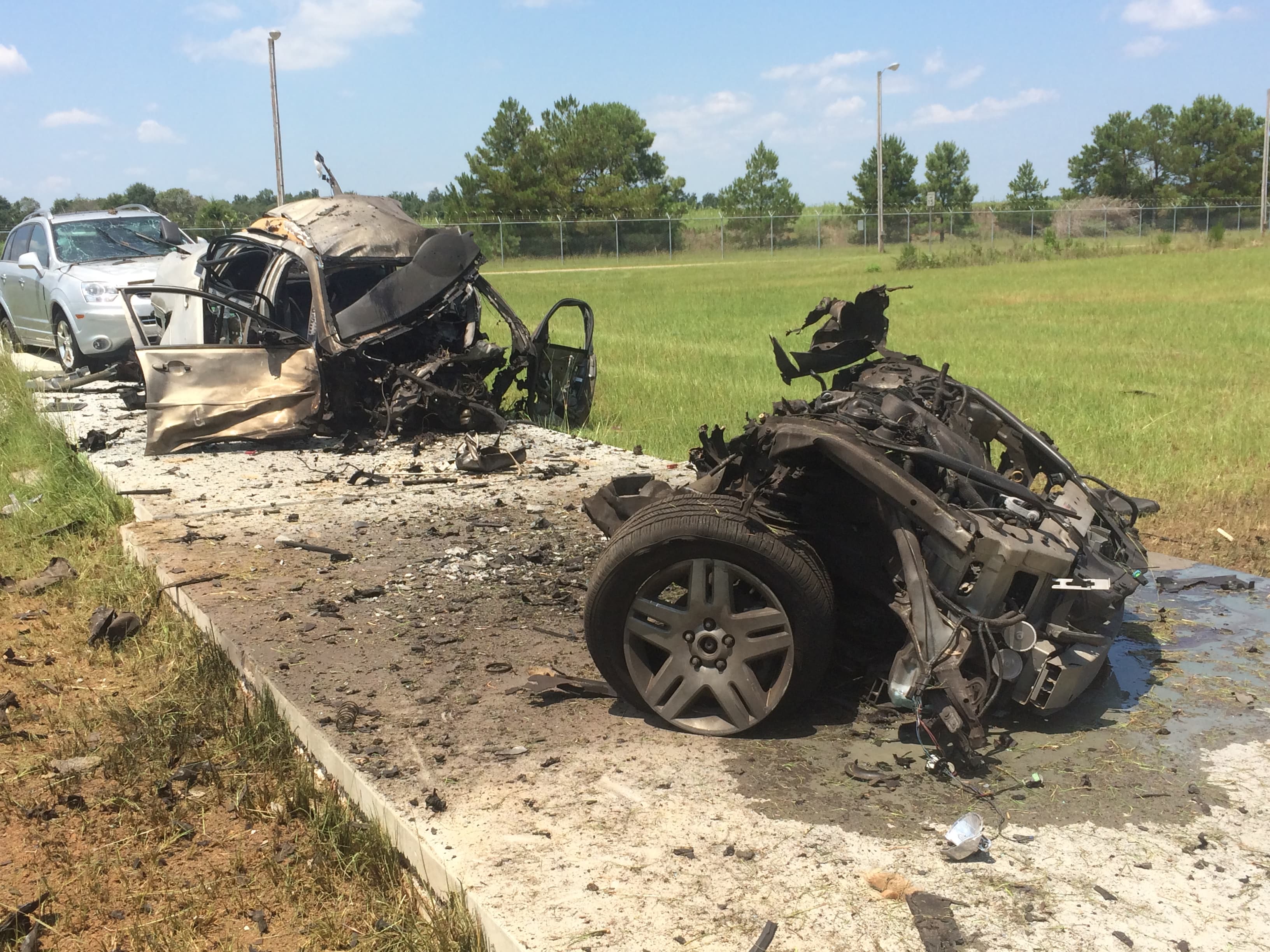 The wreckage of a vehicle after an explosive charge, its frame and axle torn apart on a concrete pad.